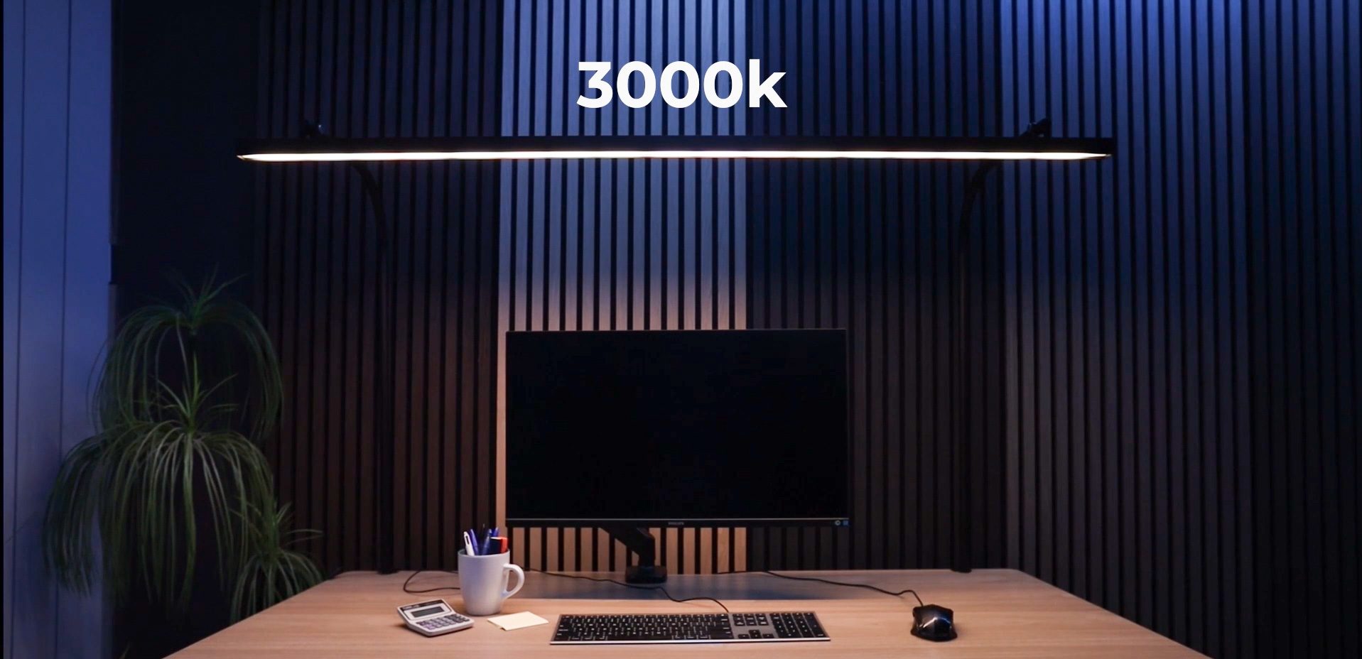 LightEFX Shift desk light set to 3000K warm white colour temperature, producing a warm amber glow over a desk with monitor and keyboard