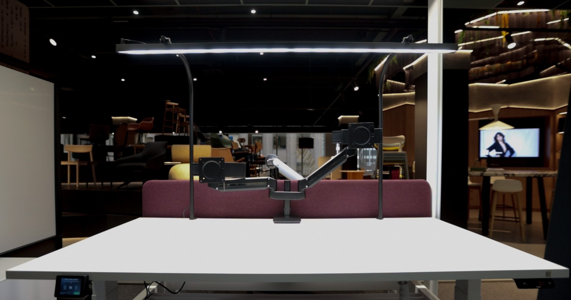 LightEFX Shift tunable desk light installed in a furniture showroom over a white workstation with monitor arm and touchpad controller